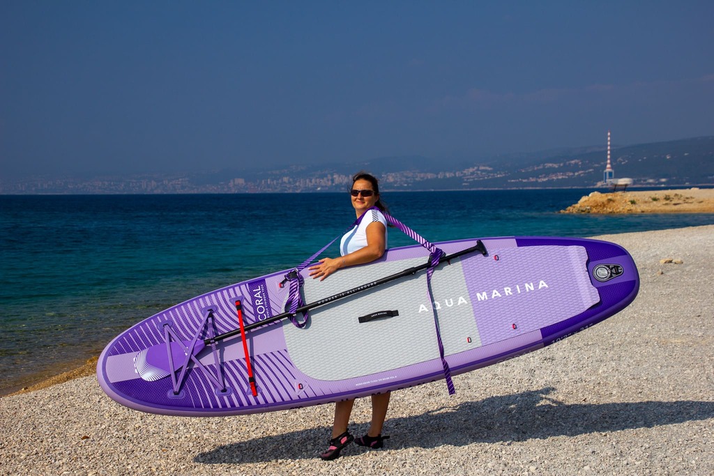 Dziewczyna z deską sup na ramieniu Aqua Marina
